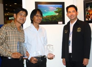 Mayor Itthiphol Kunplome and Sawat Pattiphanprasert, president of the Federation of Photographic Associations of Thailand, congratulate Sanchai Lungrung, who’s photo “Sawan Tawanork” (background) won Pattaya’s second-annual photo contest.
